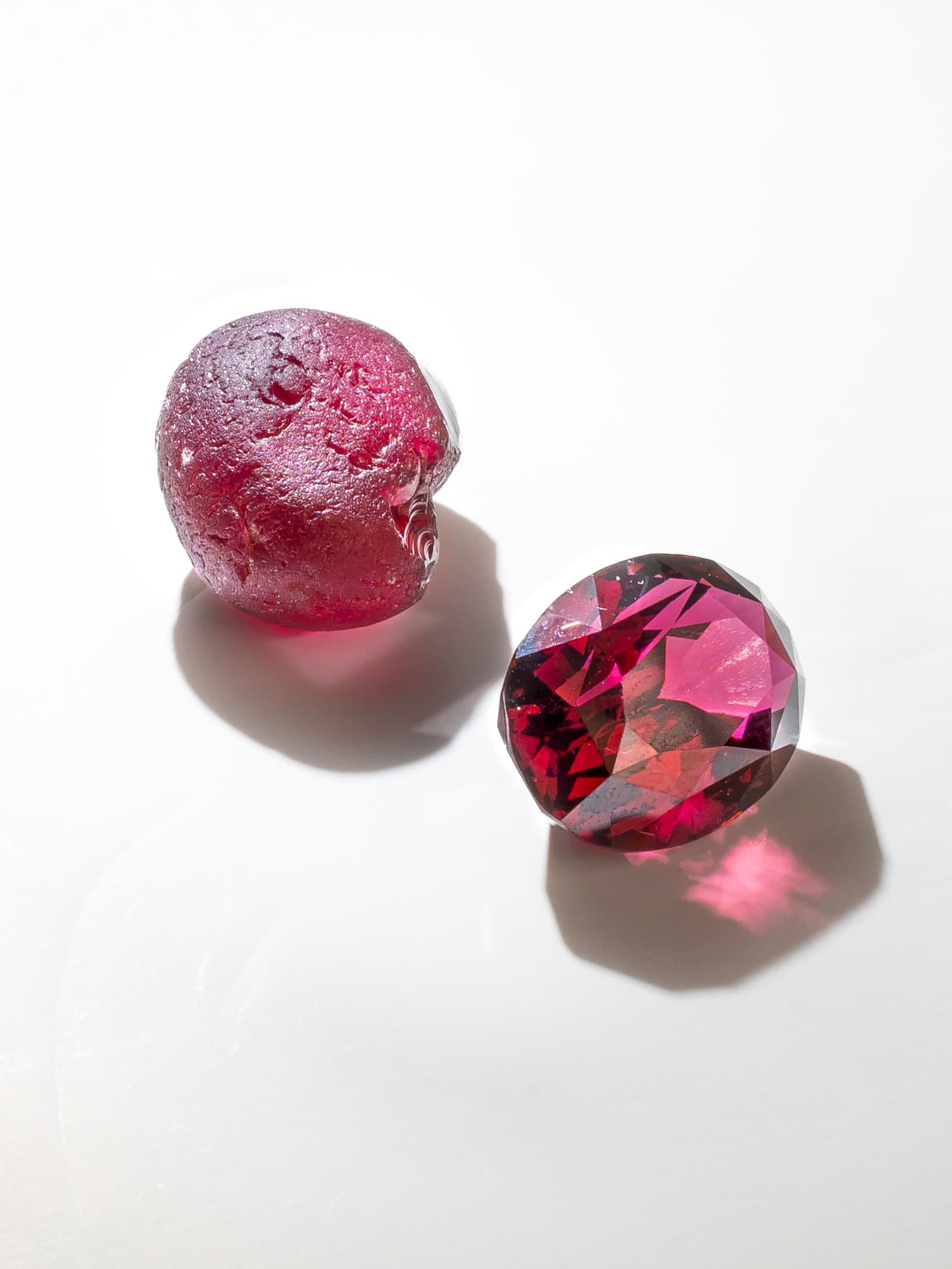 A natural gemstone shown in rough and faceted form under directional light.