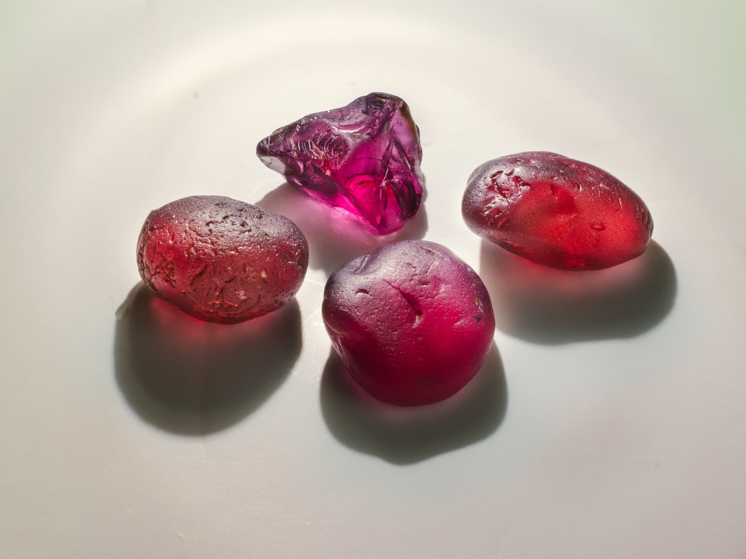 A group of richly coloured natural rough gemstones photographed under warm light.